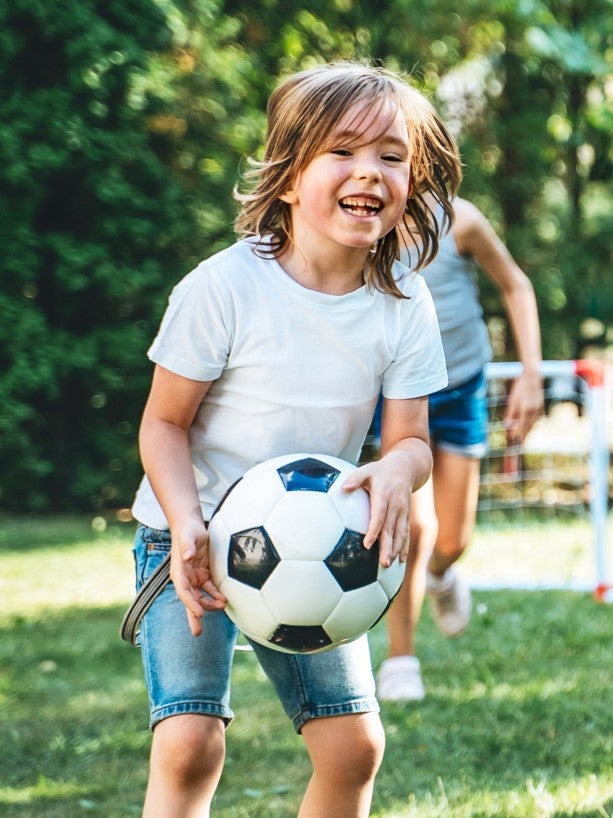 Barn som leker med en boll och ler.